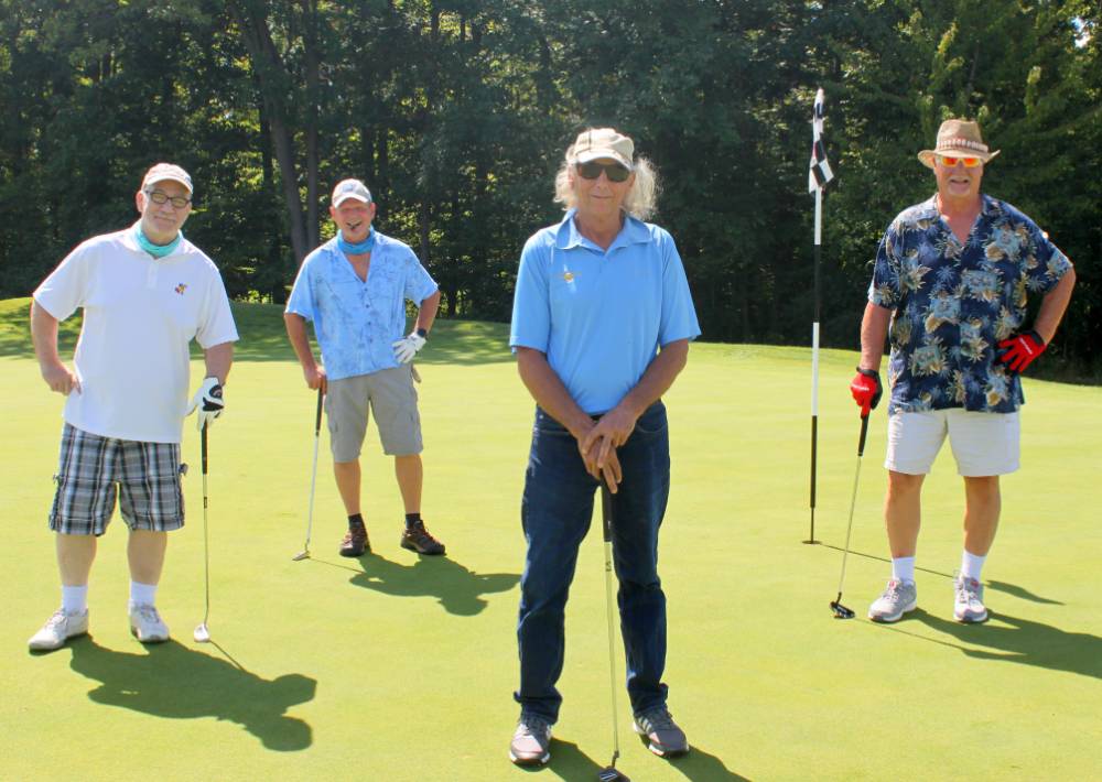 four alumni taking a picture after playing a hole